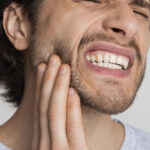 A man suffering from pain due to tooth sensitivity.